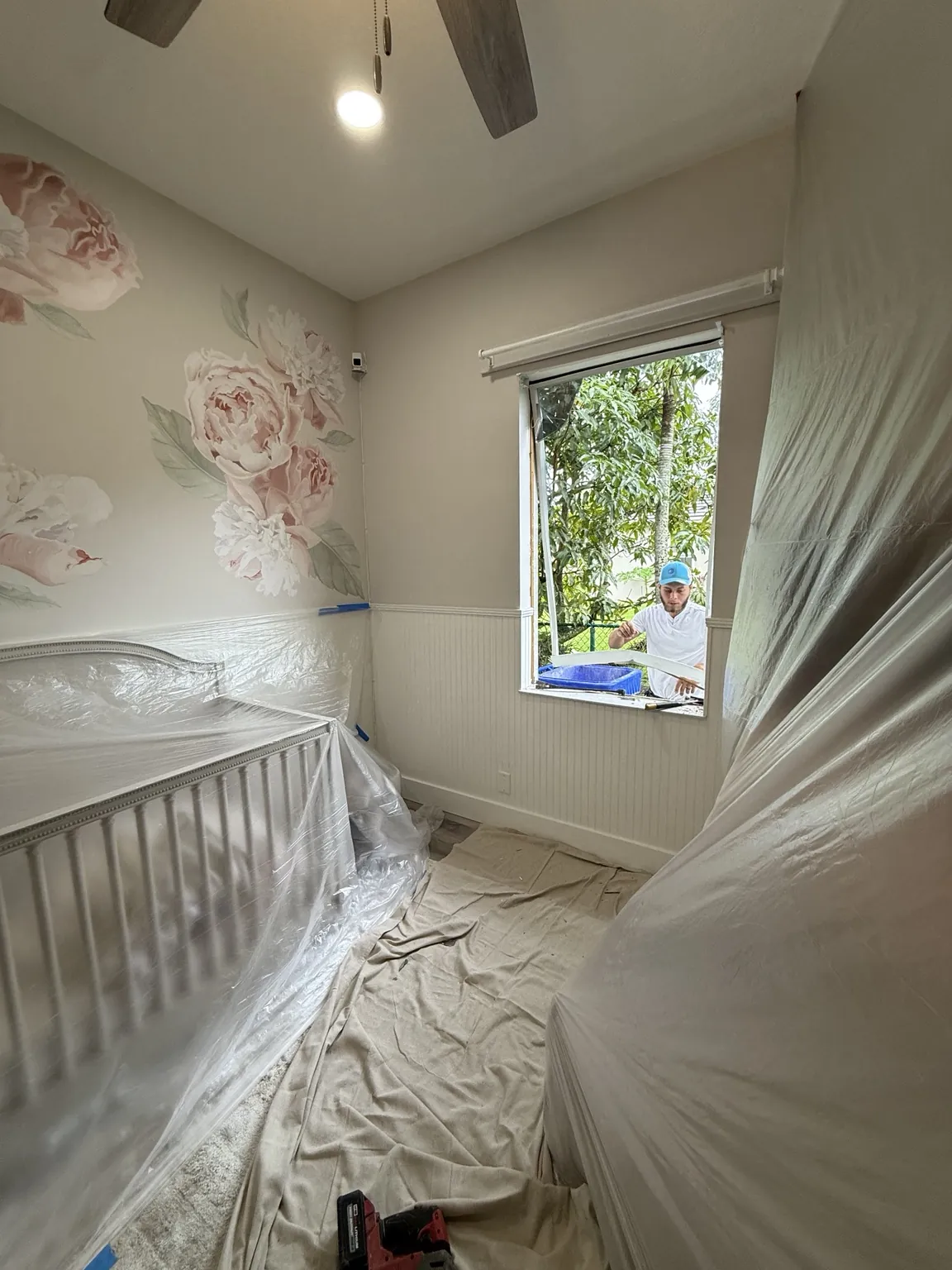 Bedroom protected with plastic sheeting and drop cloths during impact window installation